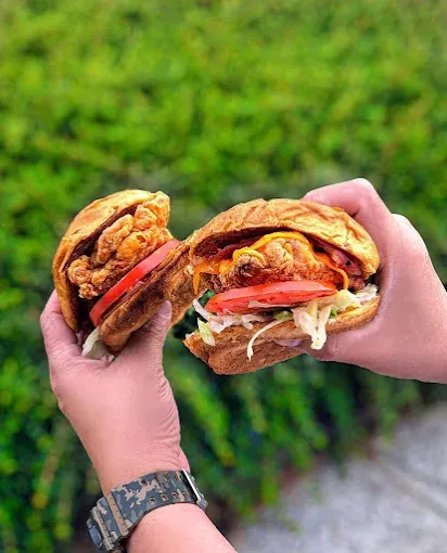Two crispy fried chicken sandwiches with tomato, slaw and lettuce on toasted buns